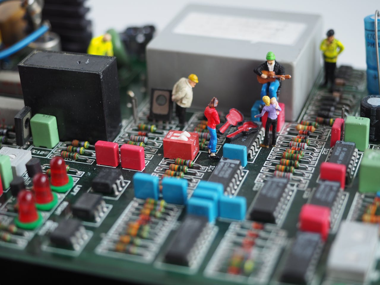Creative depiction of miniature figures working on a technological circuit board.